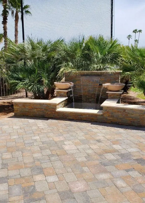 A serene patio featuring a fountain surrounded by lush palm trees, creating a tranquil outdoor space.