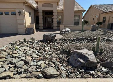 A home surrounded by rocks and cactus plants in the foreground, showcasing a desert landscape.