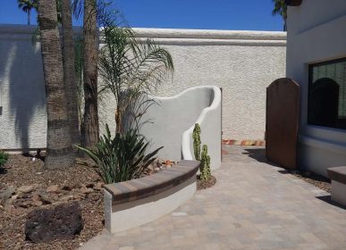 A small courtyard featuring a fountain surrounded by lush palm trees.