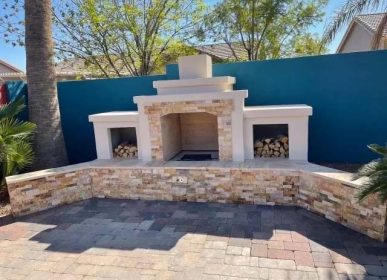 A brick fireplace in a backyard surrounded by palm trees, creating a cozy outdoor atmosphere.