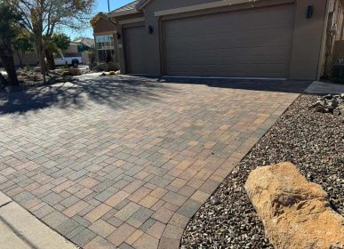 Driveway featuring brick pavers interspersed with decorative rocks, creating a textured and inviting surface.