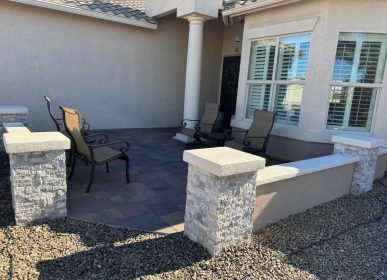 A patio featuring a stone wall and several chairs arranged for seating.